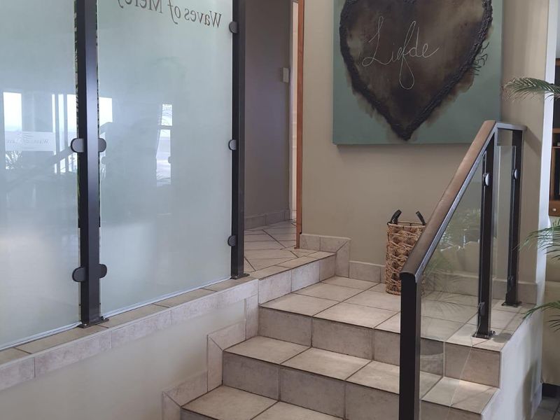 An inviting entrance area featuring a tiled staircase with a modern glass and metal balustrade and a decorative frosted glass partition.
