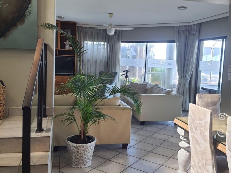Open plan living and dining area featuring tiled flooring, a staircase with a metal handrail, and sliding glass doors leading to an outdoor space.
