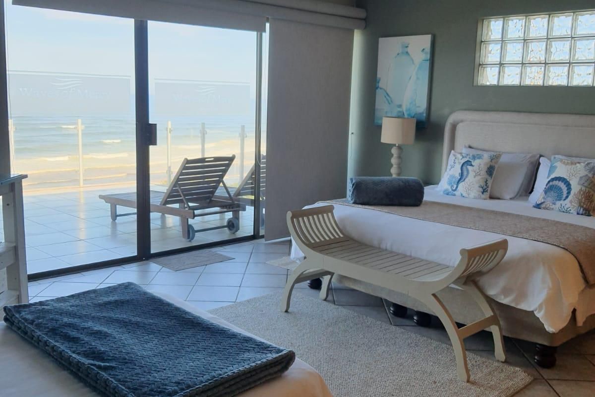 Spacious bedroom featuring tiled flooring, recessed lighting, and large sliding glass doors opening onto a balcony with direct ocean views.