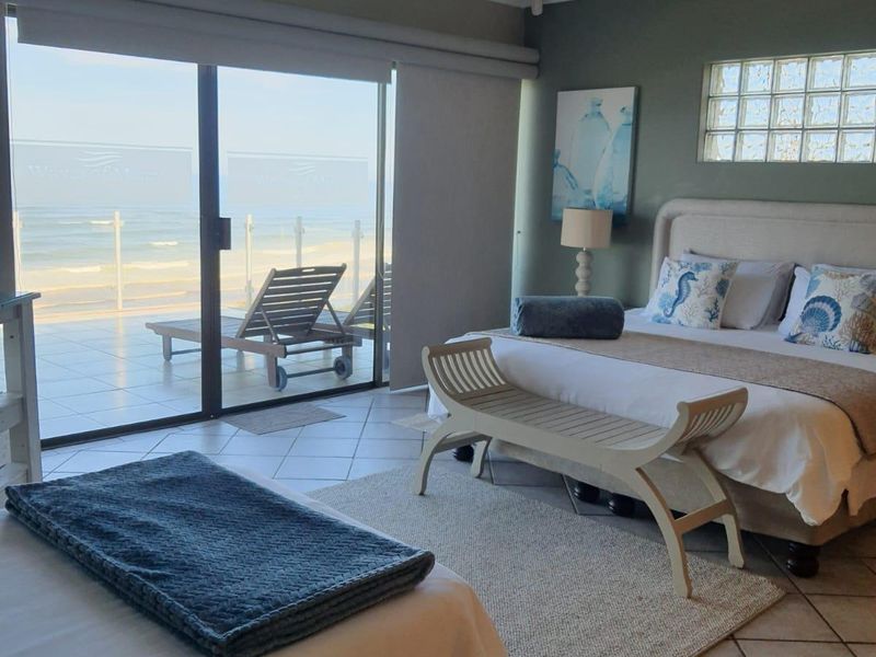 Spacious bedroom featuring tiled flooring, recessed lighting, and large sliding glass doors opening onto a balcony with direct ocean views.