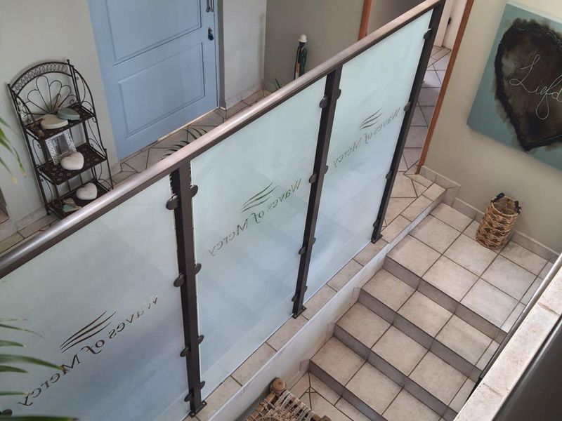 Entrance foyer featuring a tiled staircase and a modern frosted glass balustrade with a solid front door.
