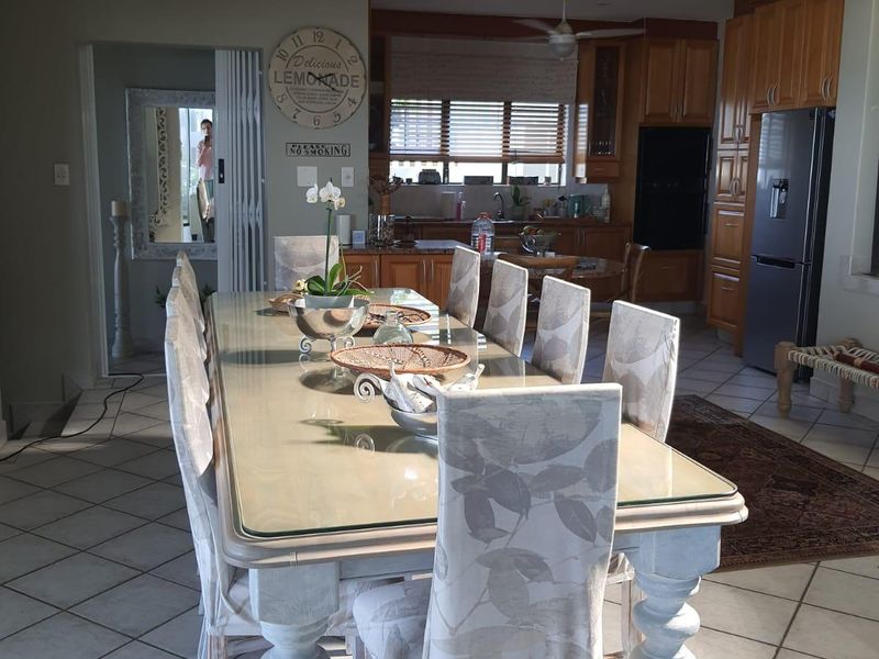 Open-plan dining and kitchen area featuring tiled flooring, wooden cabinetry, built-in appliances, and ceiling fans.