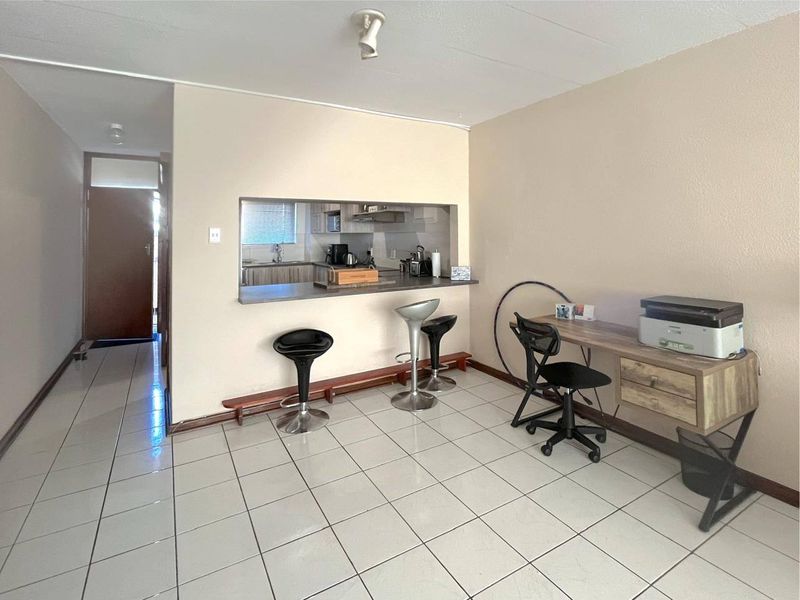 Open plan living area featuring tiled flooring and a convenient breakfast bar pass-through window connecting to the kitchen space.