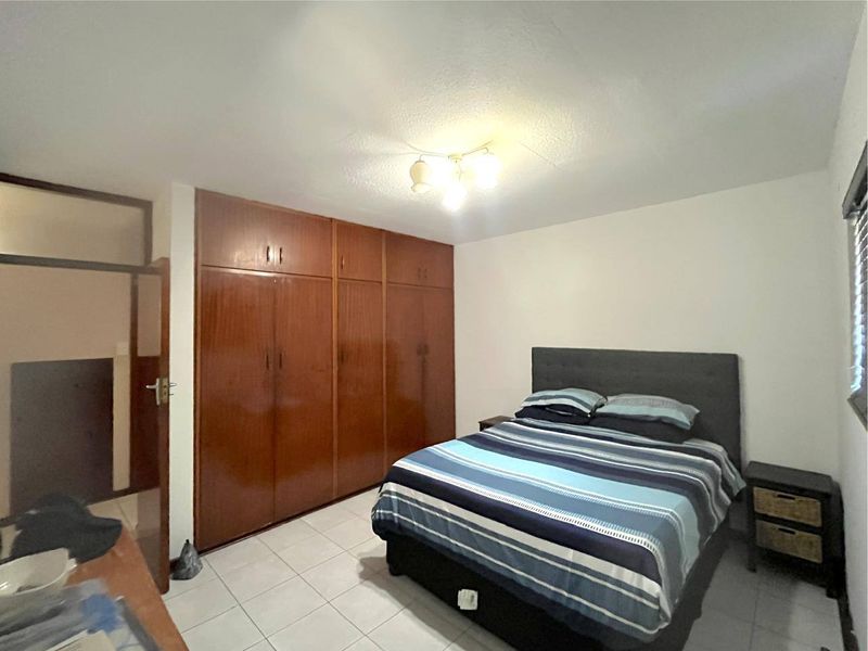 A bedroom featuring tiled flooring and extensive built-in wooden cabinetry for storage.