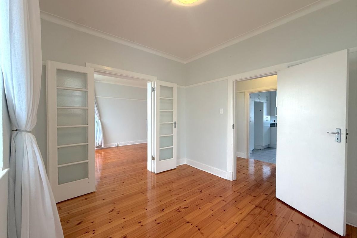 Bright and spacious living area featuring polished timber flooring, classic picture rails, and elegant french doors connecting to adjacent rooms.