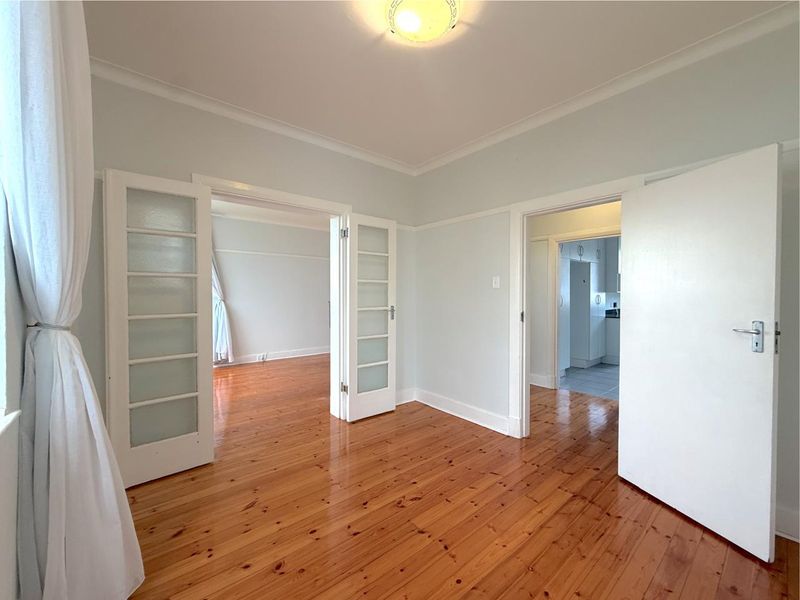 Bright and spacious living area featuring polished timber flooring, classic picture rails, and elegant french doors connecting to adjacent rooms.