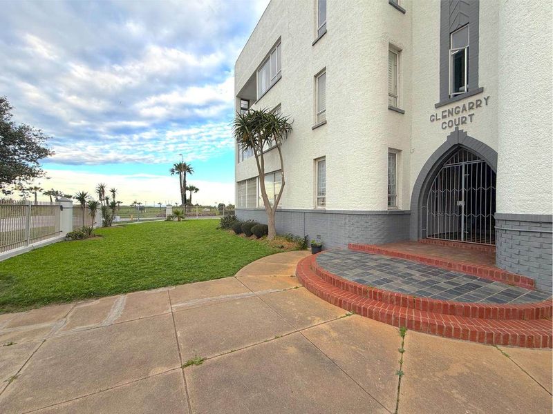 Front entrance view of Glengarry Court apartment building, featuring a secure gated entry, brick paved landing, and well-maintained lawn area.