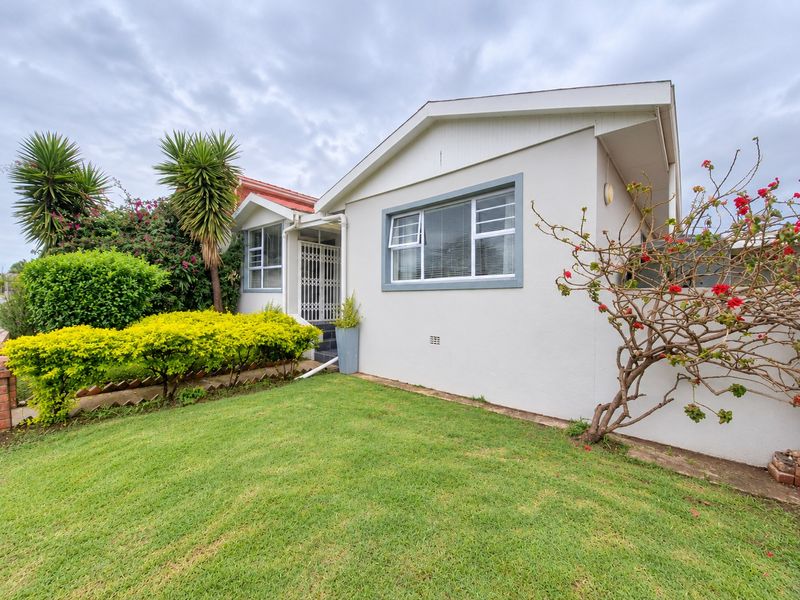 A well-maintained front exterior view of a residential house featuring a neat lawn, established garden, and secure entrance.