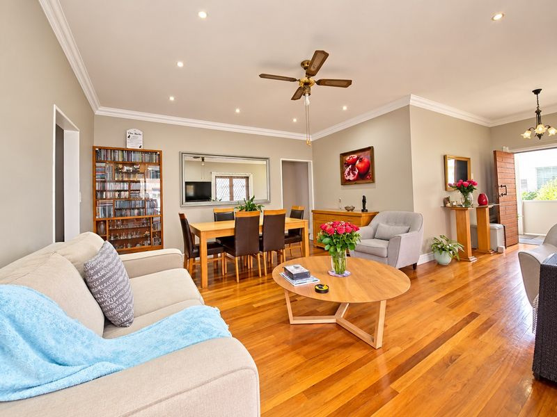 Spacious open-plan living and dining area featuring polished hardwood flooring, recessed lighting, and elegant crown molding throughout.