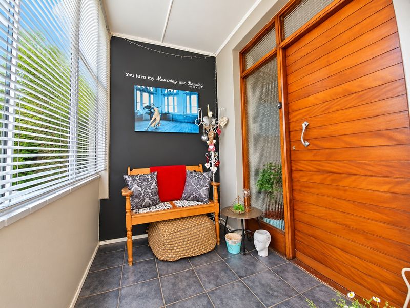 A bright entrance foyer featuring a solid timber front door with textured glass sidelight and durable tiled flooring.
