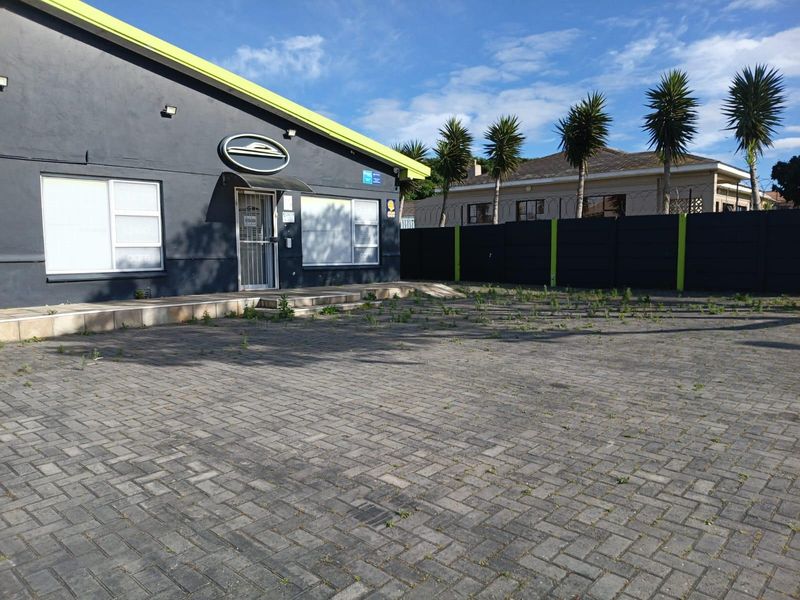 Front exterior view of the property featuring a paved driveway, security perimeter wall with razor wire, and a tiled entrance area.