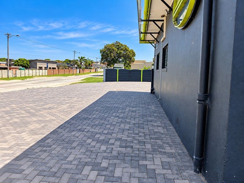 A well-maintained paved driveway and exterior side elevation of the property, featuring modern dark finishes and secure boundary fencing.