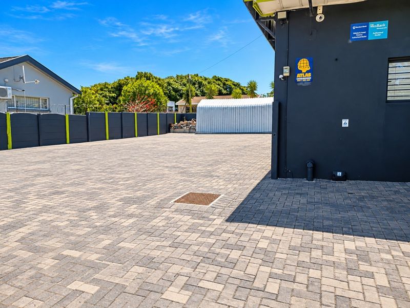 A spacious, well-maintained paved rear yard featuring a perimeter wall, security camera, and a detached metal storage shed.