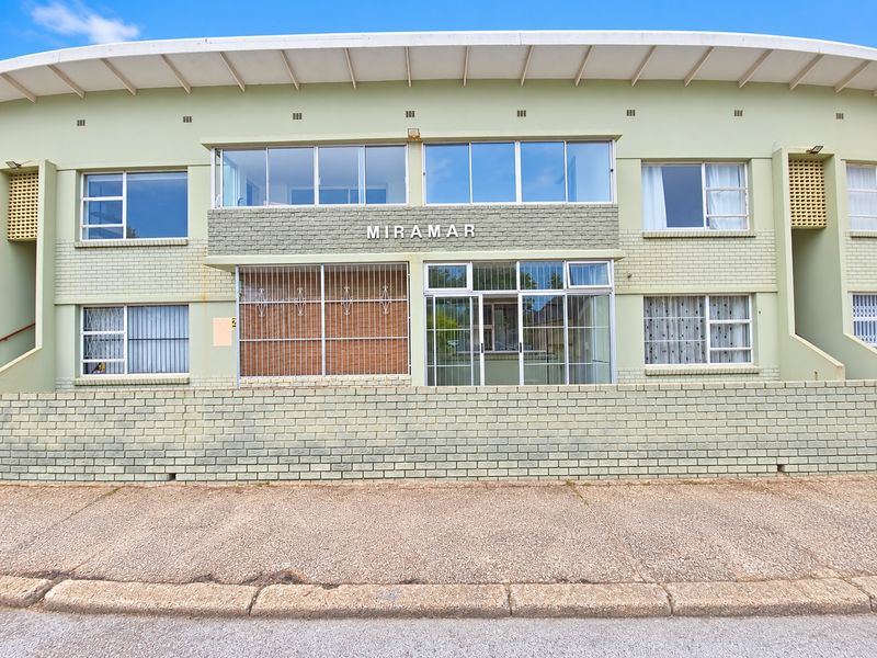 Front elevation of the Miramar apartment building featuring a brick facade, security bars on ground floor windows, and a low brick boundary wall.