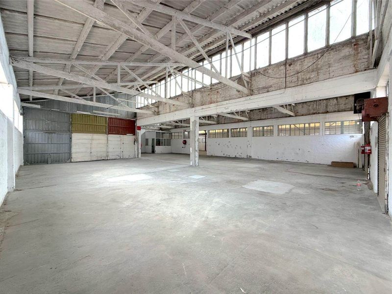 Spacious industrial warehouse featuring high ceilings with exposed timber trusses, clerestory windows for natural light, and durable concrete flooring.