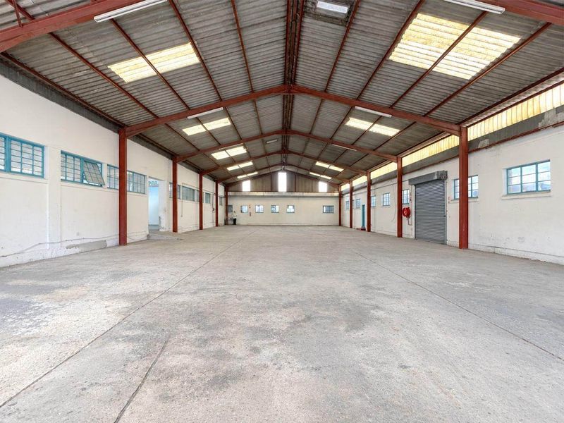 Spacious industrial warehouse featuring a high-clearance steel portal frame, concrete flooring, integrated skylights, and a large roller shutter door for efficient access.