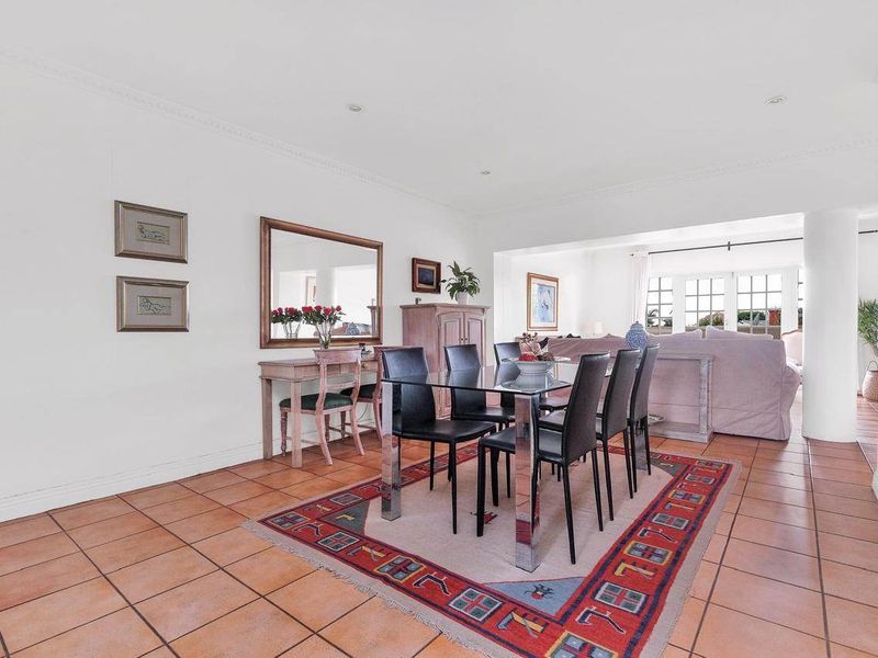 Spacious open-plan living and dining area featuring terracotta floor tiles, recessed lighting, and crown molding, creating a bright and inviting atmosphere.