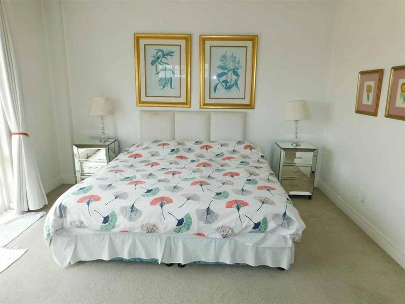 A well-lit bedroom featuring neutral carpeting and white walls, providing a clean and simple foundation for personal styling.
