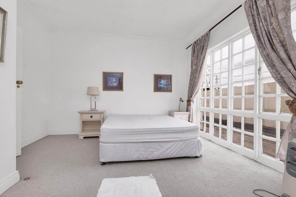 A bright bedroom featuring neutral carpet flooring, crown molding, and a large multi-pane glass door providing access to an outdoor area.