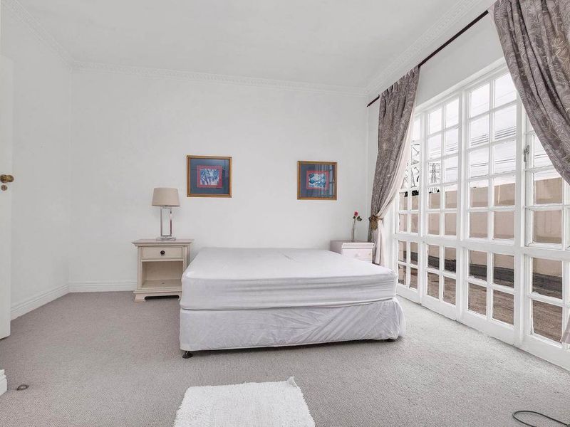 A bright bedroom featuring neutral carpet flooring, crown molding, and a large multi-pane glass door providing access to an outdoor area.