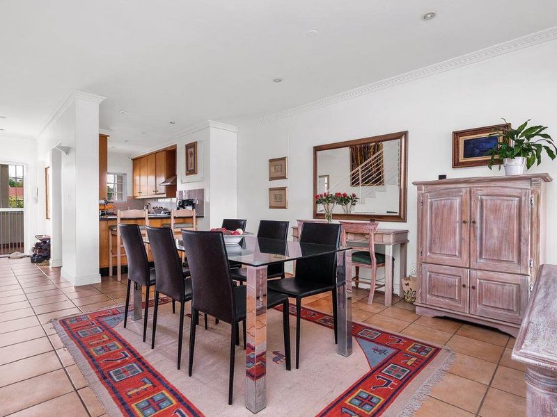 Open plan living and dining area featuring tiled floors, crown molding, and a connected kitchen with breakfast bar, leading to an outdoor balcony.