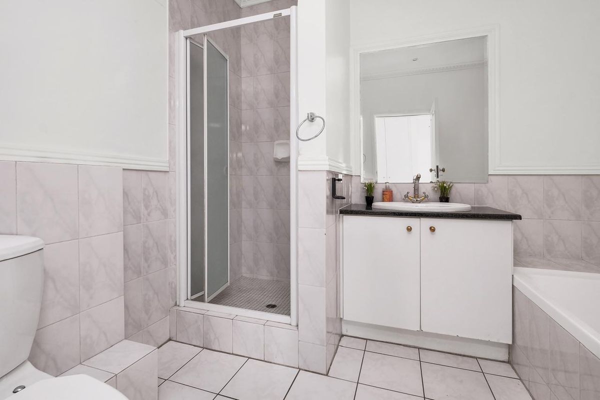 A functional bathroom featuring a shower enclosure, vanity with basin, bathtub, and neutral wall and floor tiling.