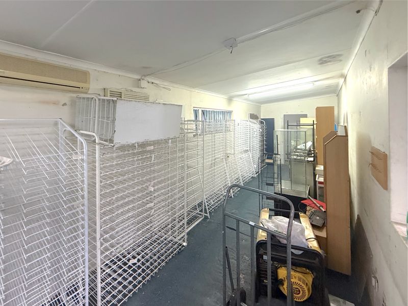 A utility or storage space featuring wall-mounted air conditioning, fluorescent lighting, and carpeted flooring, currently used for commercial storage.