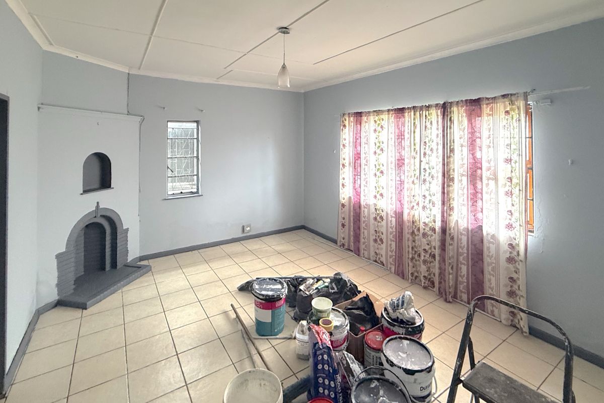 Spacious living room featuring tiled flooring and a built-in fireplace, currently undergoing renovation with a neutral color palette.