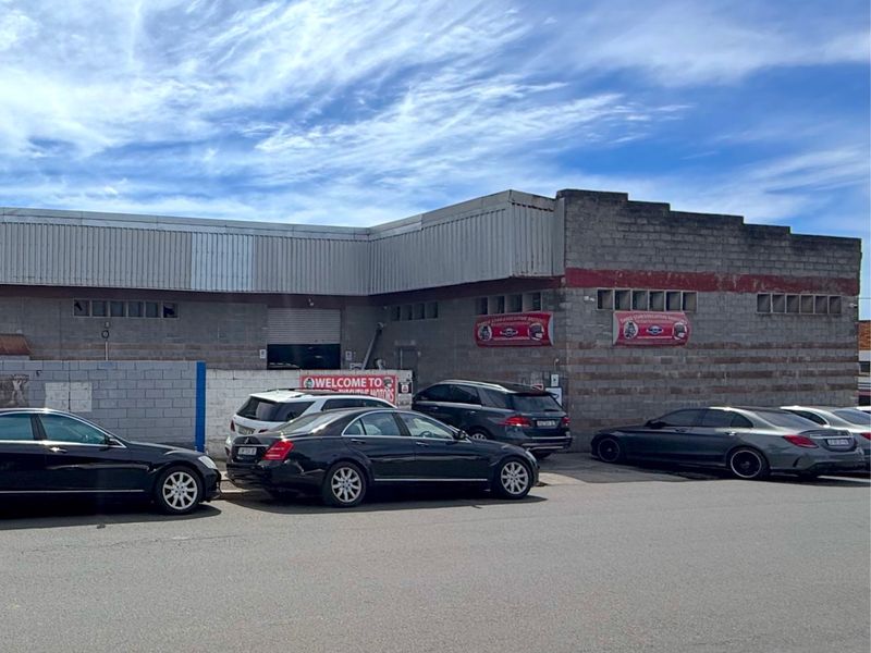 Front elevation of a commercial industrial building featuring concrete block construction, metal cladding, and a roller shutter entrance.