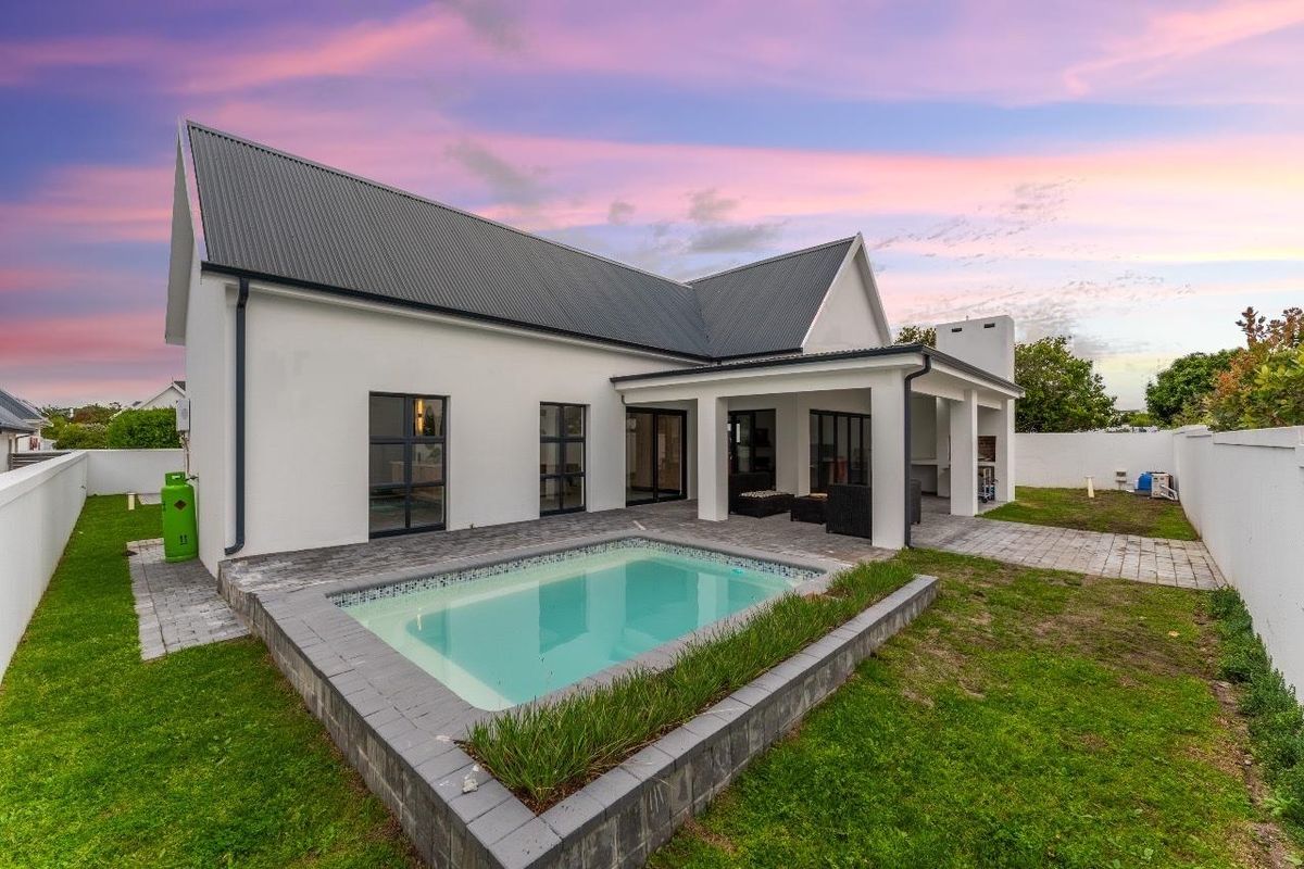 Rear view of the property featuring a swimming pool, paved patio area, and a covered outdoor space with a built-in braai.