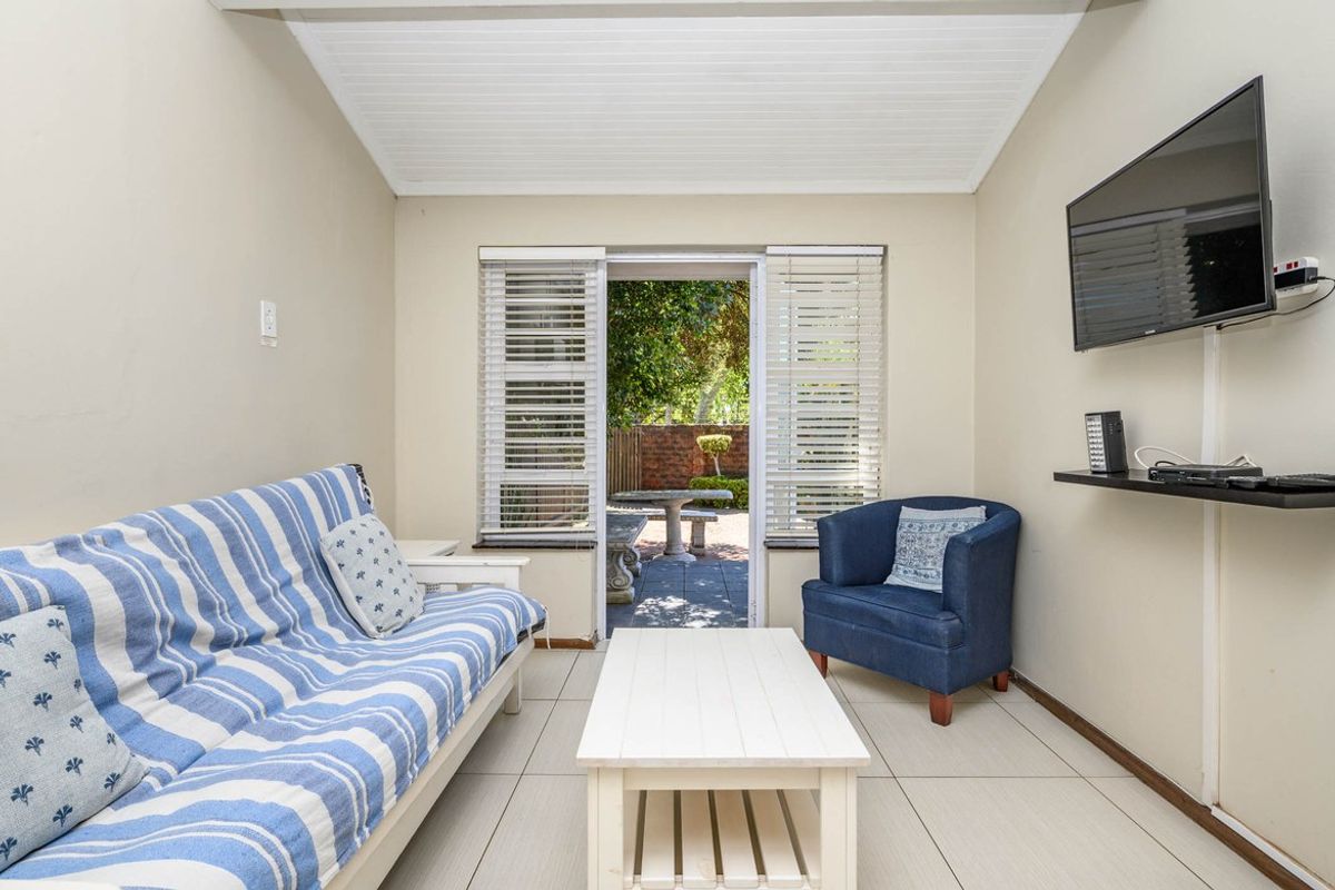 A cozy living room featuring tiled flooring, a tongue-and-groove ceiling, and direct access to an outdoor patio area through sliding doors.