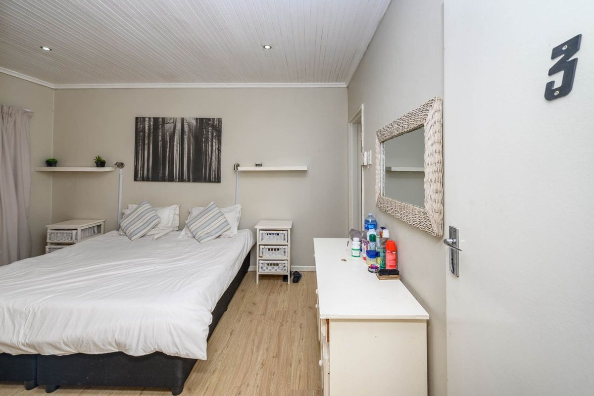 A bedroom featuring wood-look laminate flooring, a tongue-and-groove panelled ceiling with recessed lighting, and built-in shelving.