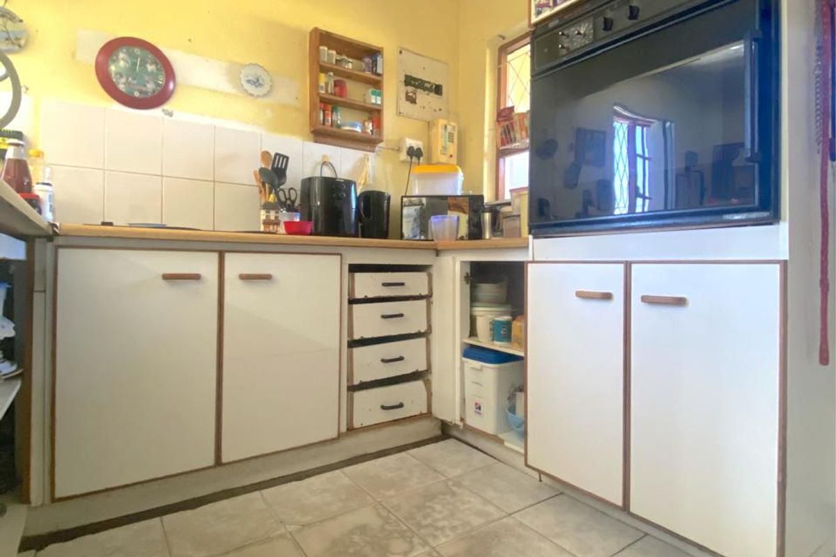 A dated kitchen featuring white cabinetry, built-in oven, tiled backsplash, and ceramic floor tiles, offering potential for a modern renovation.