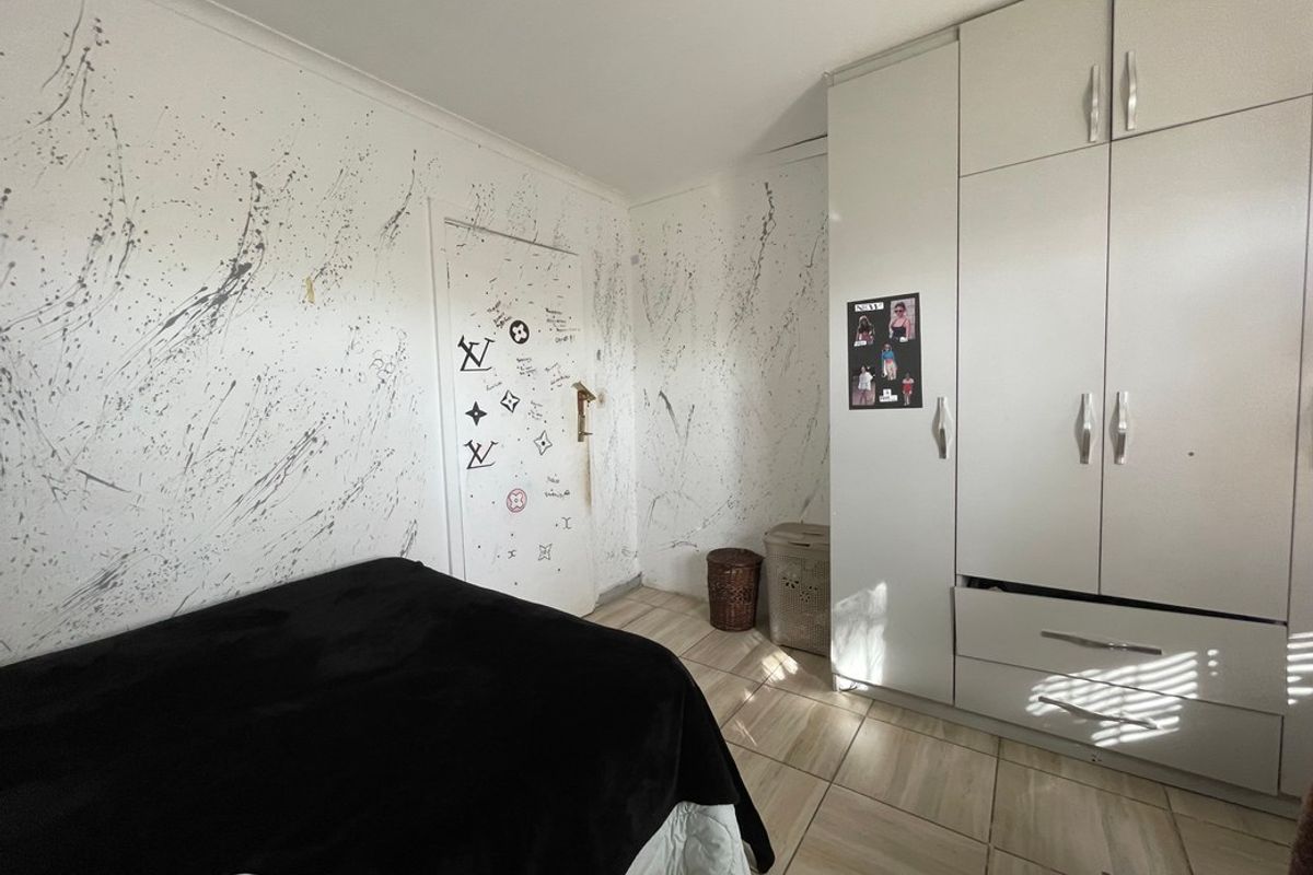 A bedroom featuring built-in cabinetry and tiled flooring, currently requiring cosmetic updates to the wall finishes and door surfaces.