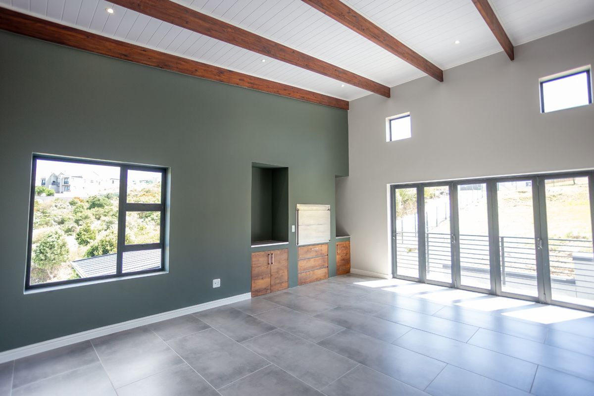 Spacious living area featuring high vaulted ceilings with exposed timber beams, large windows, tiled flooring, and built-in cabinetry with a recessed display niche.