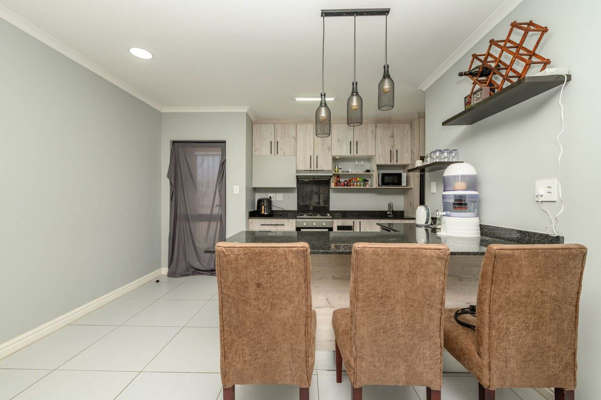 Modern kitchen featuring light wood-grain cabinetry, granite countertops, a breakfast bar, and integrated lighting, creating a functional and contemporary culinary space.