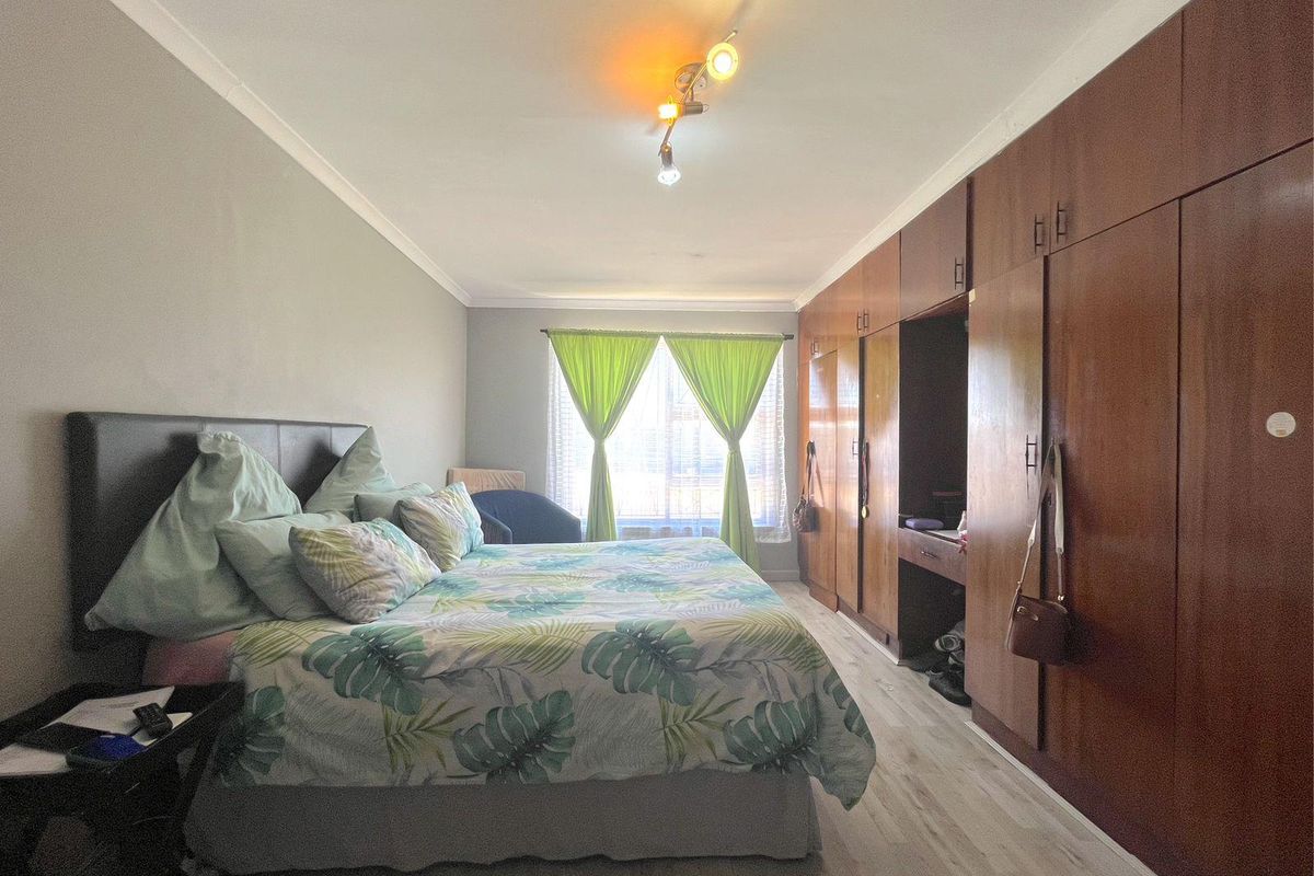 A bedroom featuring extensive built-in wooden cabinetry and light-toned laminate flooring, providing ample storage space.