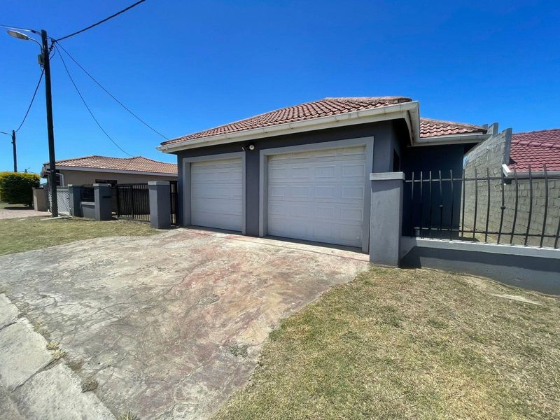 Front view of a residential property featuring a double garage, tiled roof, and a concrete driveway with perimeter fencing.