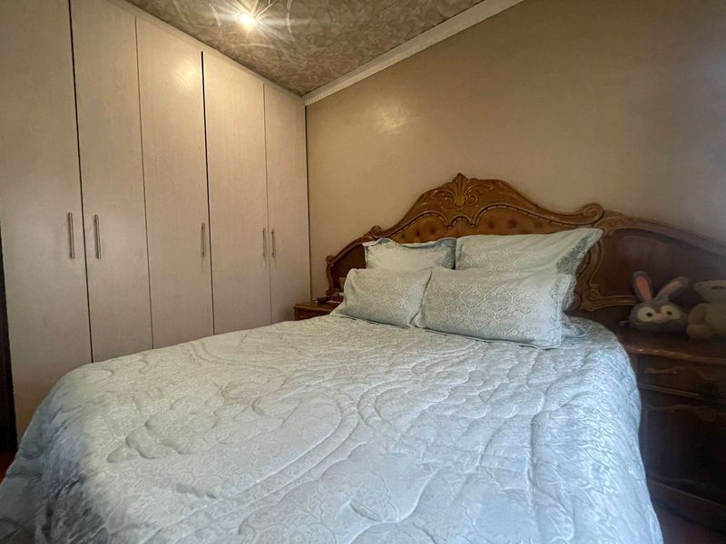 A bedroom featuring built-in wardrobes and a textured ceiling finish.