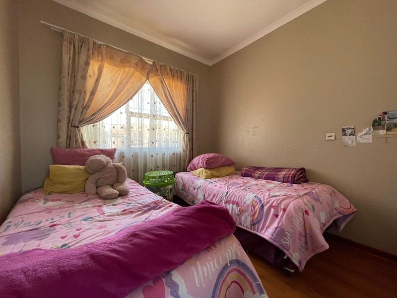 A functional bedroom featuring laminate flooring and a window with a curtain rod, providing a comfortable space for rest.