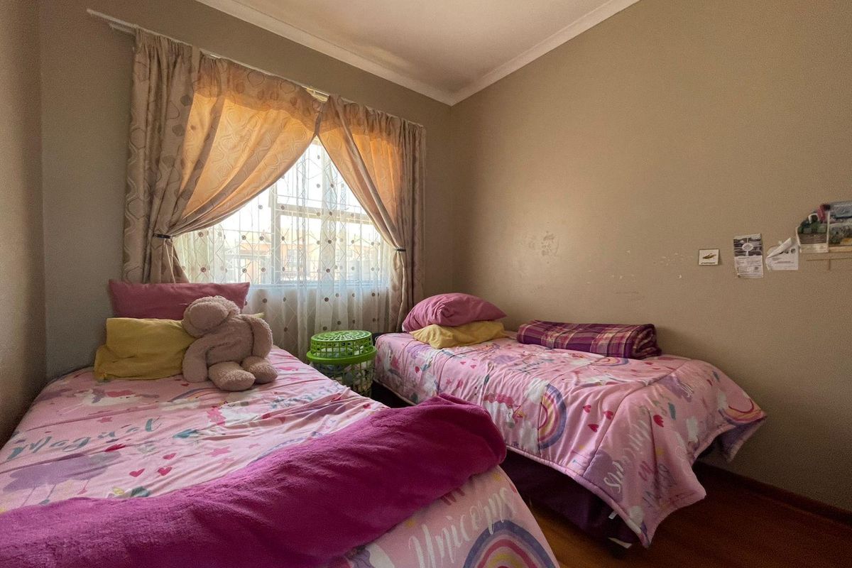 A functional bedroom featuring laminate flooring and a window with a curtain rod, providing a comfortable space for rest.
