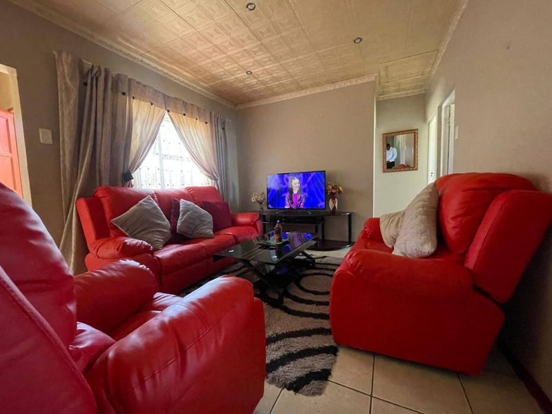 A living room featuring tiled flooring and a textured ceiling, providing a functional and lived-in space.