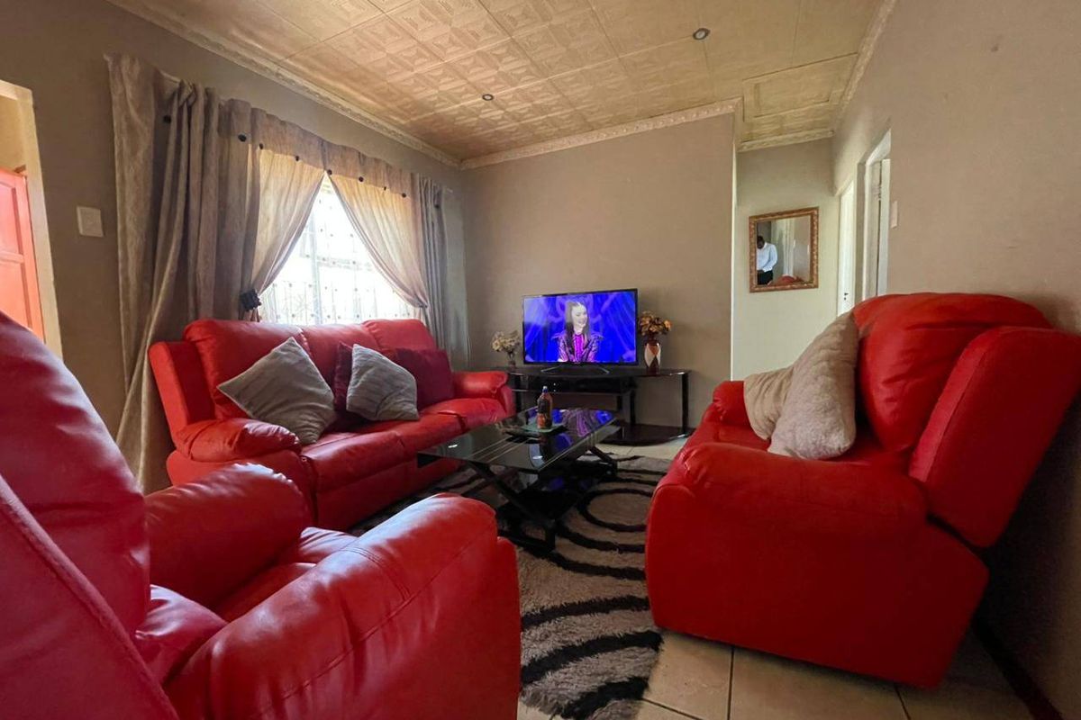 A living room featuring tiled flooring and a textured ceiling, providing a functional and lived-in space.