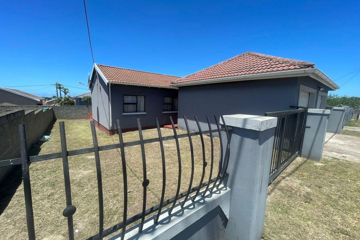 Rear view of the property featuring a tiled roof, enclosed garden area with perimeter walling, and metal security gate access.