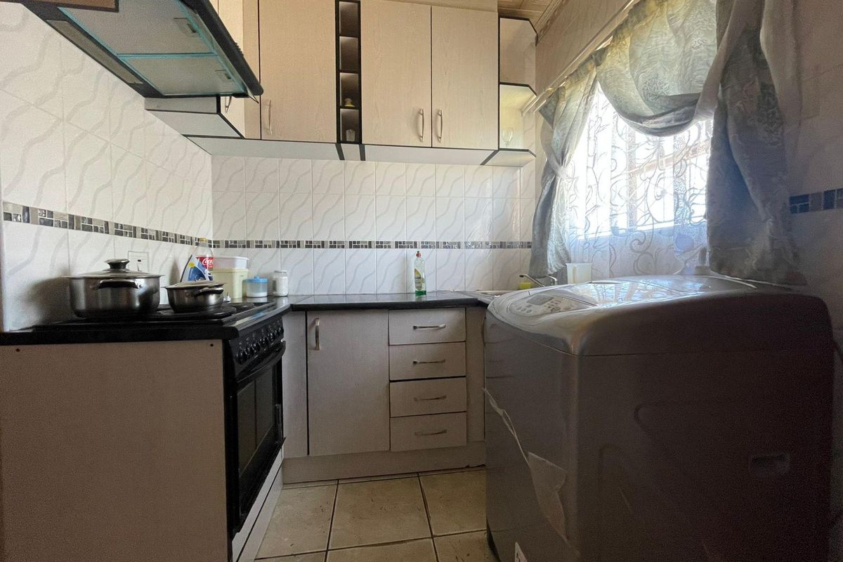 Compact kitchen featuring built-in cabinetry, tiled splashbacks, and integrated stove with extractor fan, offering a functional layout with potential for modernization.