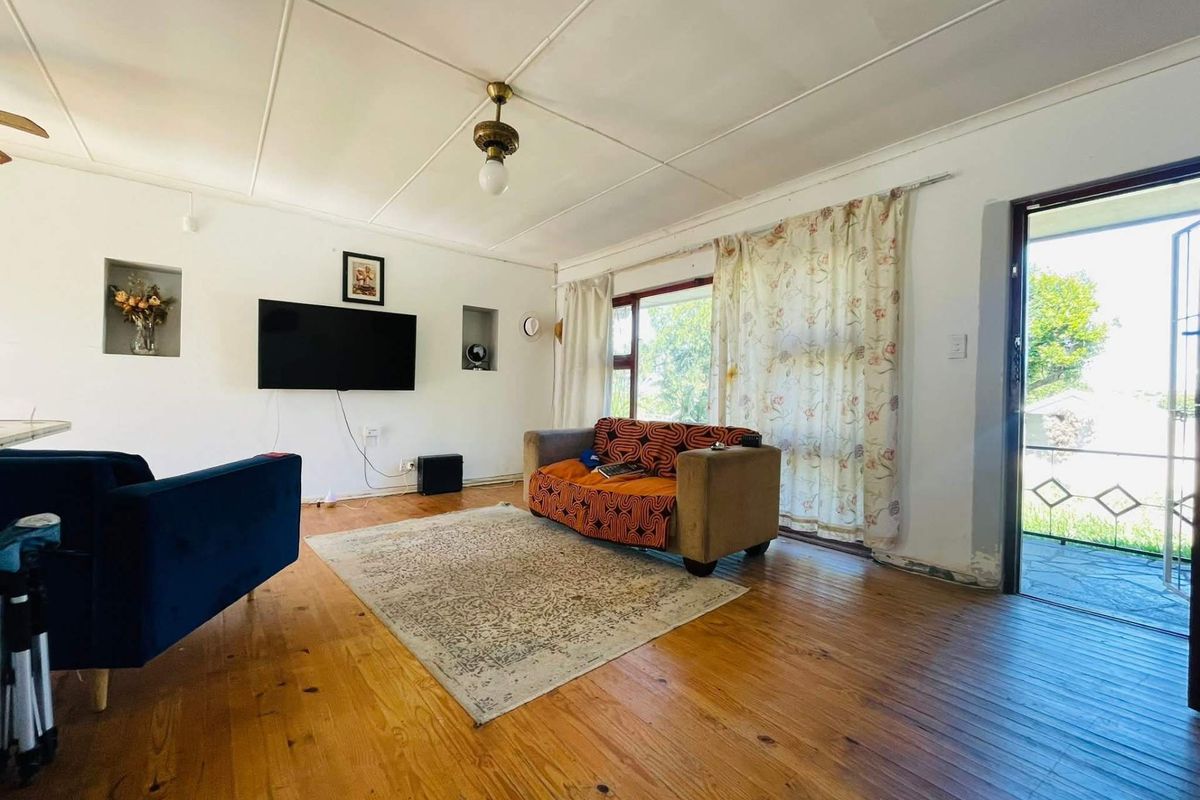A living room featuring timber flooring, recessed wall niches, and direct access to an outdoor area through a glass door.