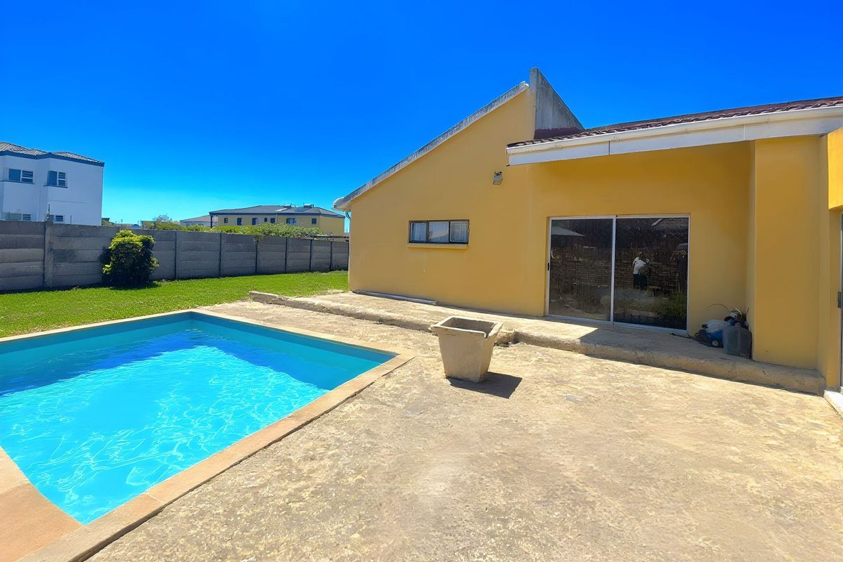Rear exterior view featuring a swimming pool, concrete patio area, and sliding glass door access to the main dwelling.