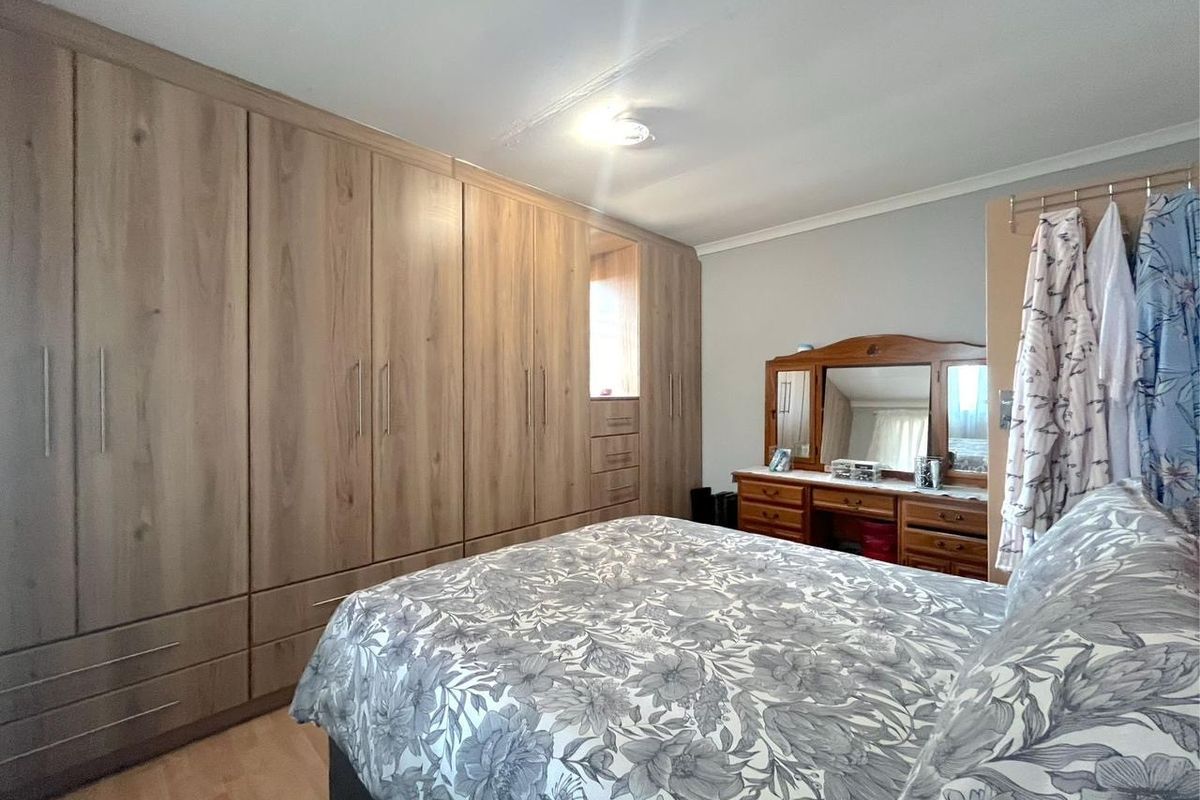A well-maintained bedroom featuring extensive floor-to-ceiling built-in wooden cabinetry and light-toned laminate flooring.