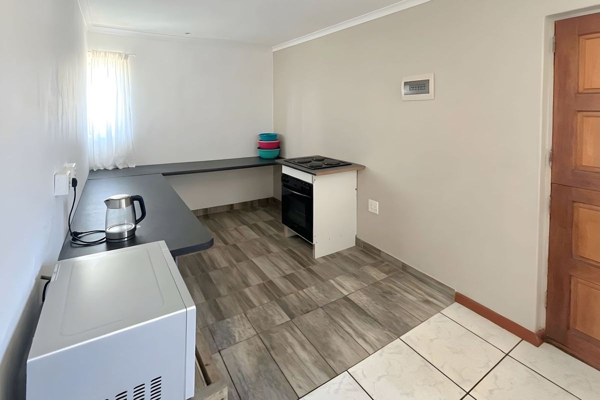 A functional kitchen area featuring a built-in oven and hob, extended laminate countertops, and tiled flooring.