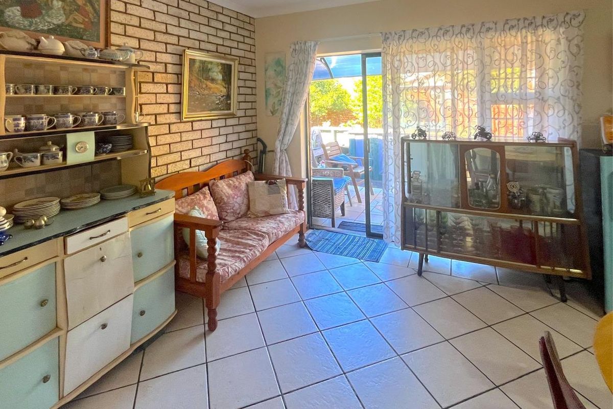 Living area featuring exposed brick wall, ceramic floor tiles, and sliding glass door access to the patio.